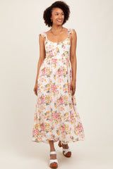 woman wearing a floral maxi dress with ruffled straps and a fitted waist, standing against a light background