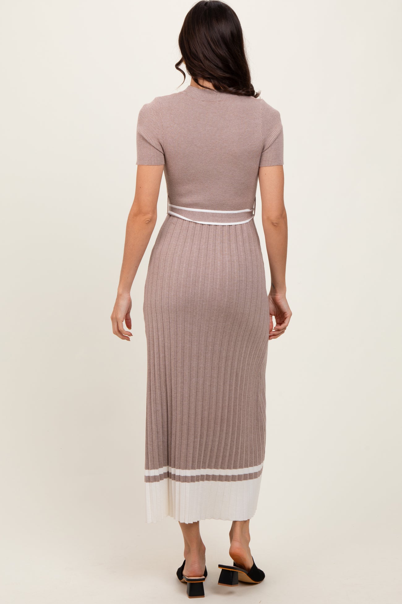 woman wearing a ribbed midi dress in taupe with a fitted design and white stripe detail at the hem