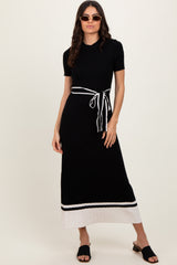 woman wearing a black ribbed knit maxi dress with a white striped hem and a tie waist detail, paired with sunglasses