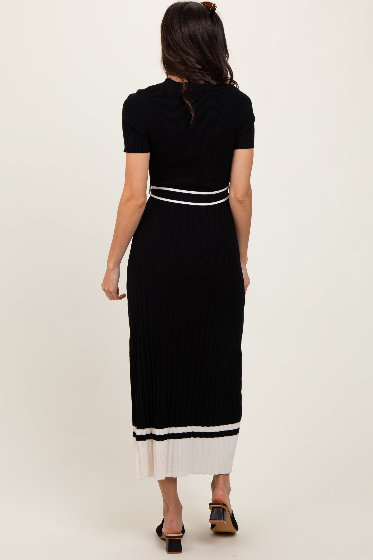 woman wearing a black ribbed midi dress with short sleeves and white stripe detailing at the hem