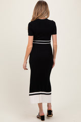 woman wearing a black ribbed maternity dress with short sleeves and color-blocked hem details, showing a baby bump