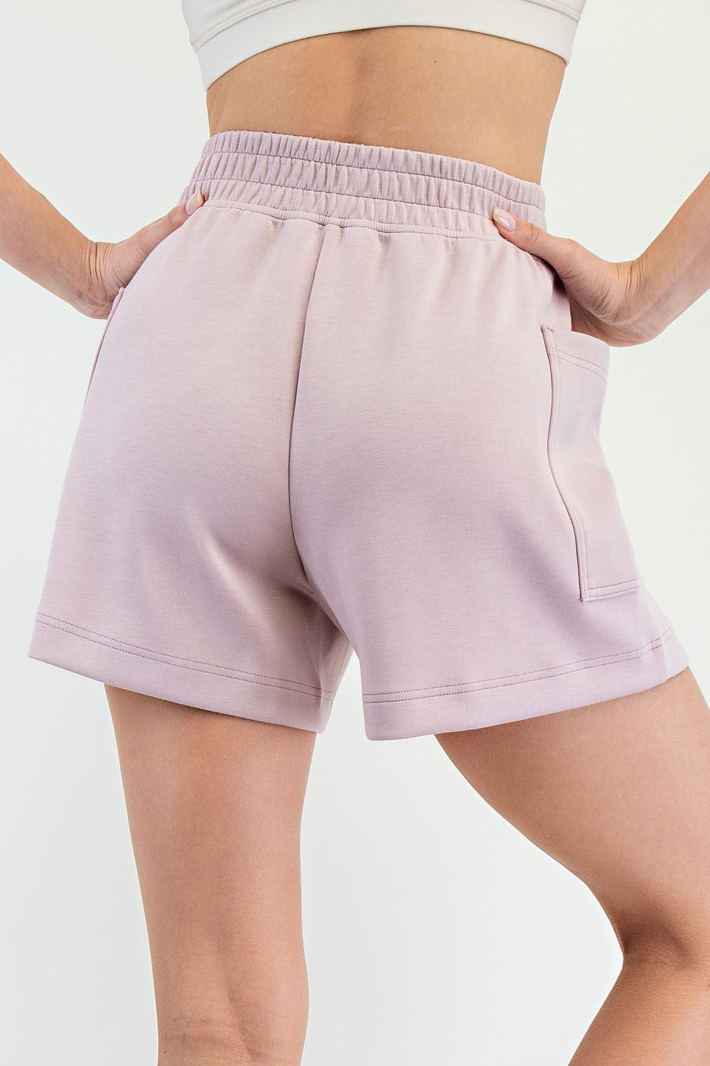 woman wearing light pink elastic waist shorts with a back pocket, showing the back view