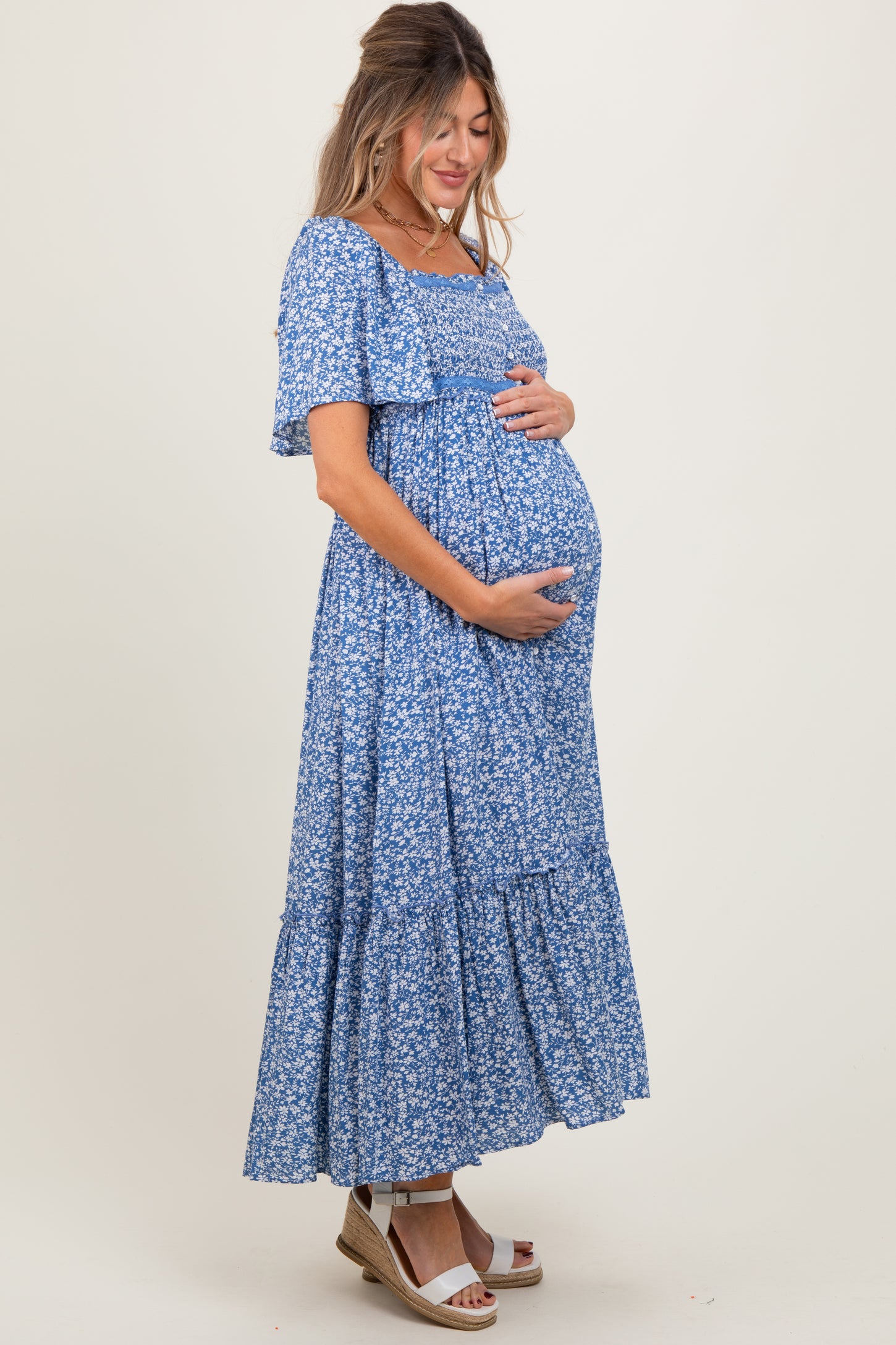 woman wearing a blue floral maternity maxi dress and holding her baby bump