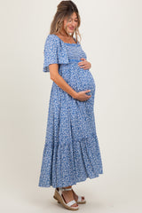 woman wearing a blue floral maternity maxi dress and holding her baby bump