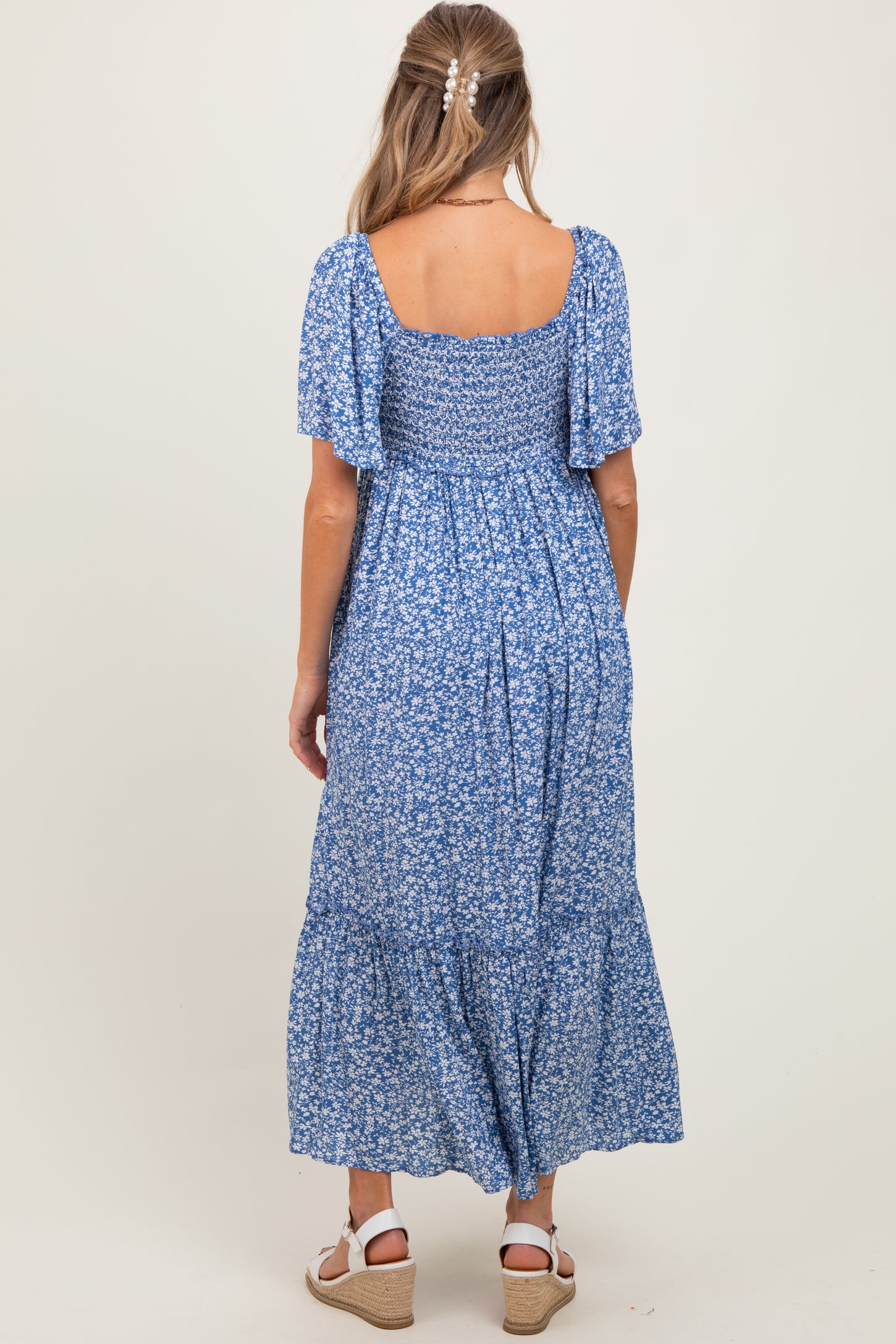 woman wearing a blue floral maxi maternity dress with short flutter sleeves and a smocked bodice
