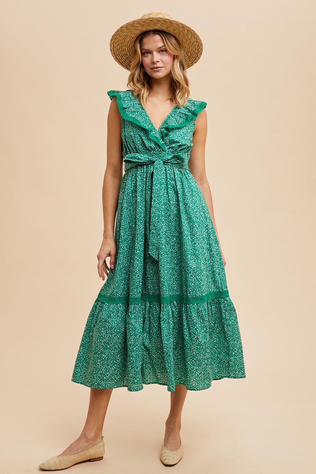 woman wearing a green floral midi dress with ruffled sleeves and a tied waist, paired with a straw hat and shoes