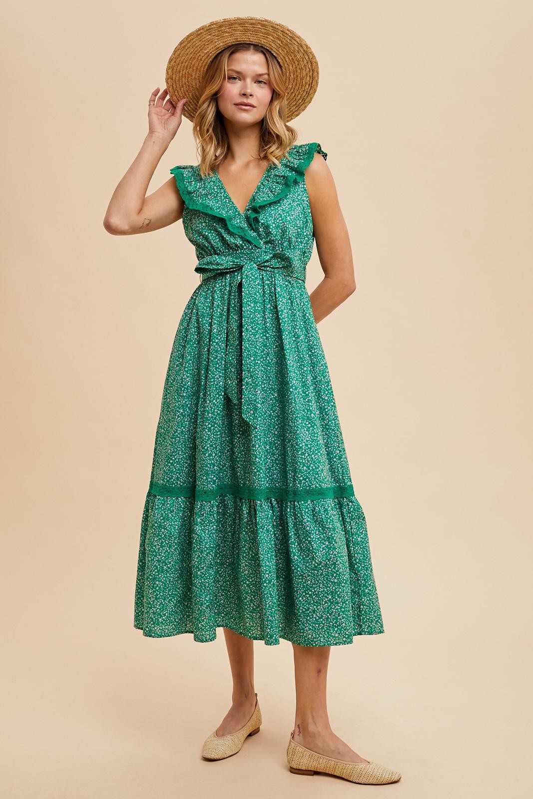 woman wearing a green floral midi dress with ruffled sleeves and a belted waist, styled with a straw hat