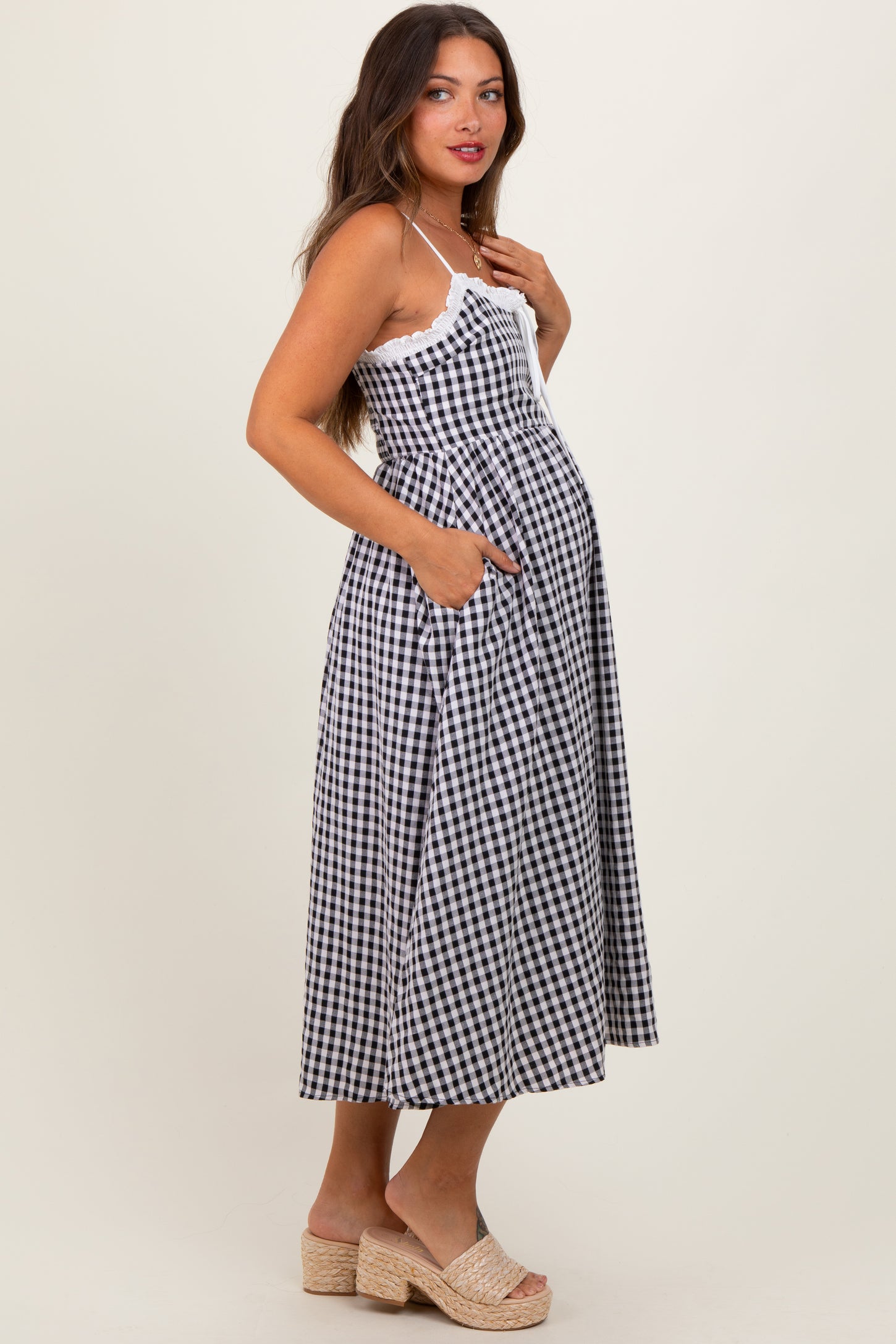 woman wearing a black and white gingham maternity dress with pockets and a visible baby bump