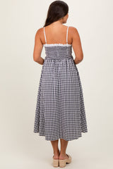 woman wearing a black and white gingham maternity maxi dress with spaghetti straps and a smocked back