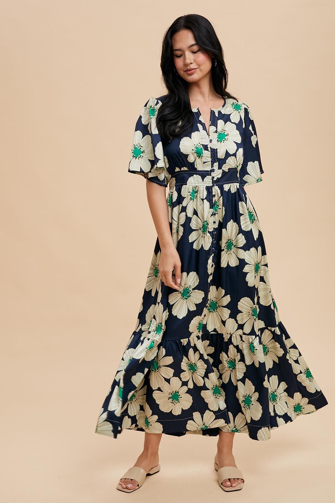 woman wearing a navy floral maxi dress with short sleeves and a cinched waist, styled with flat sandals