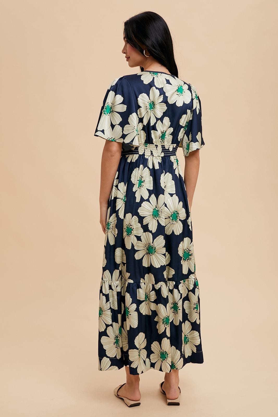 woman wearing a navy floral maxi dress with short flutter sleeves and a tiered skirt from the back