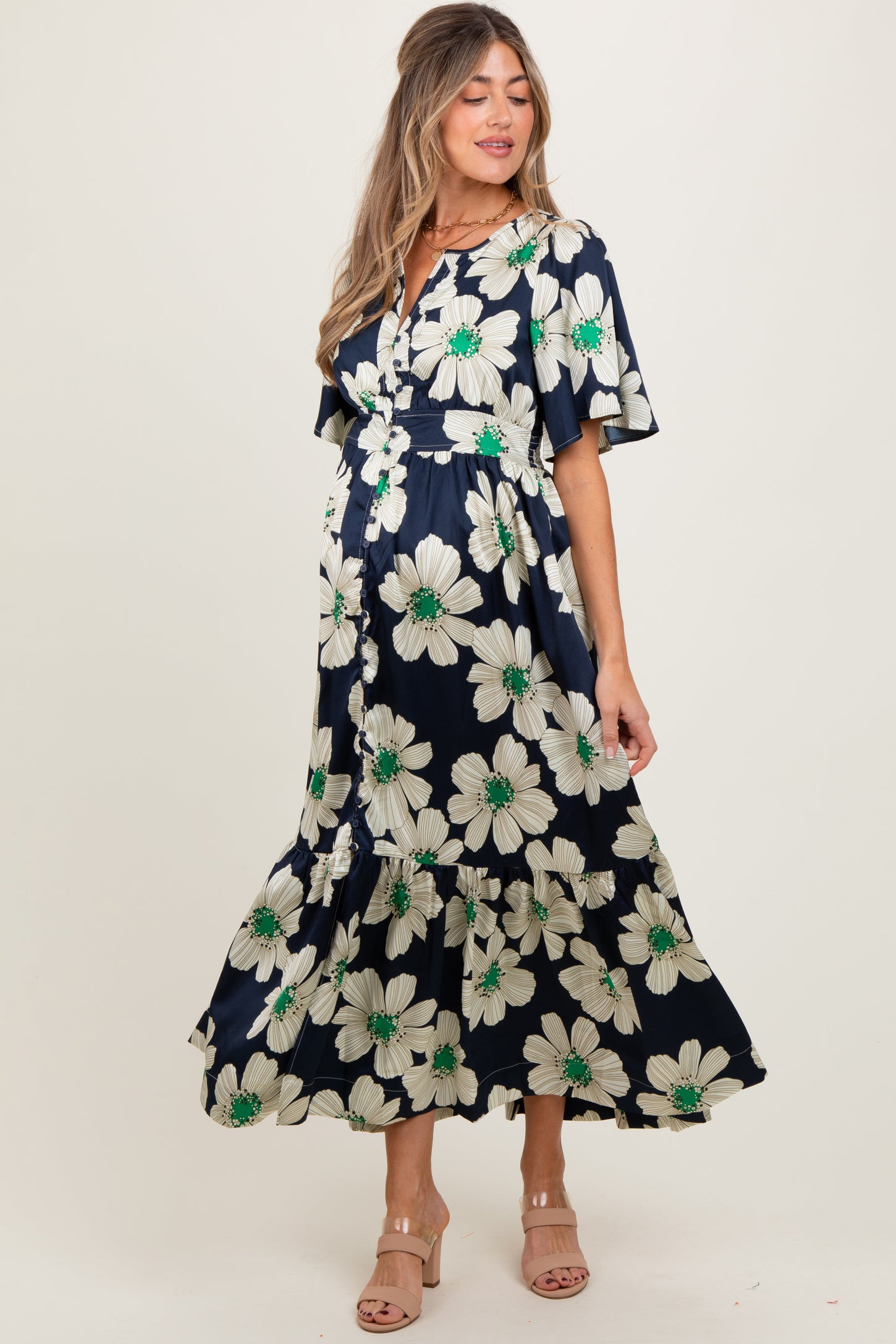 woman wearing a navy floral maternity dress with short sleeves and a tiered skirt, showcasing her baby bump
