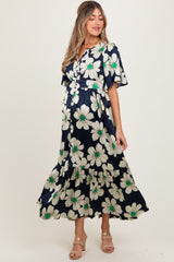 woman wearing a navy floral maternity dress with short sleeves and a tiered skirt, showcasing her baby bump