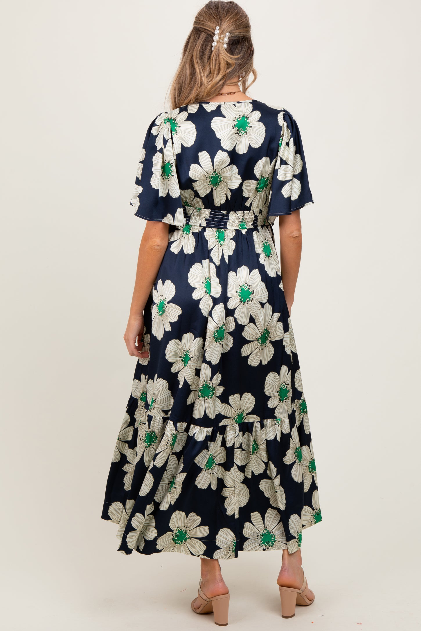 woman wearing a navy floral maternity dress with short sleeves and a tiered skirt, showing a baby bump from behind