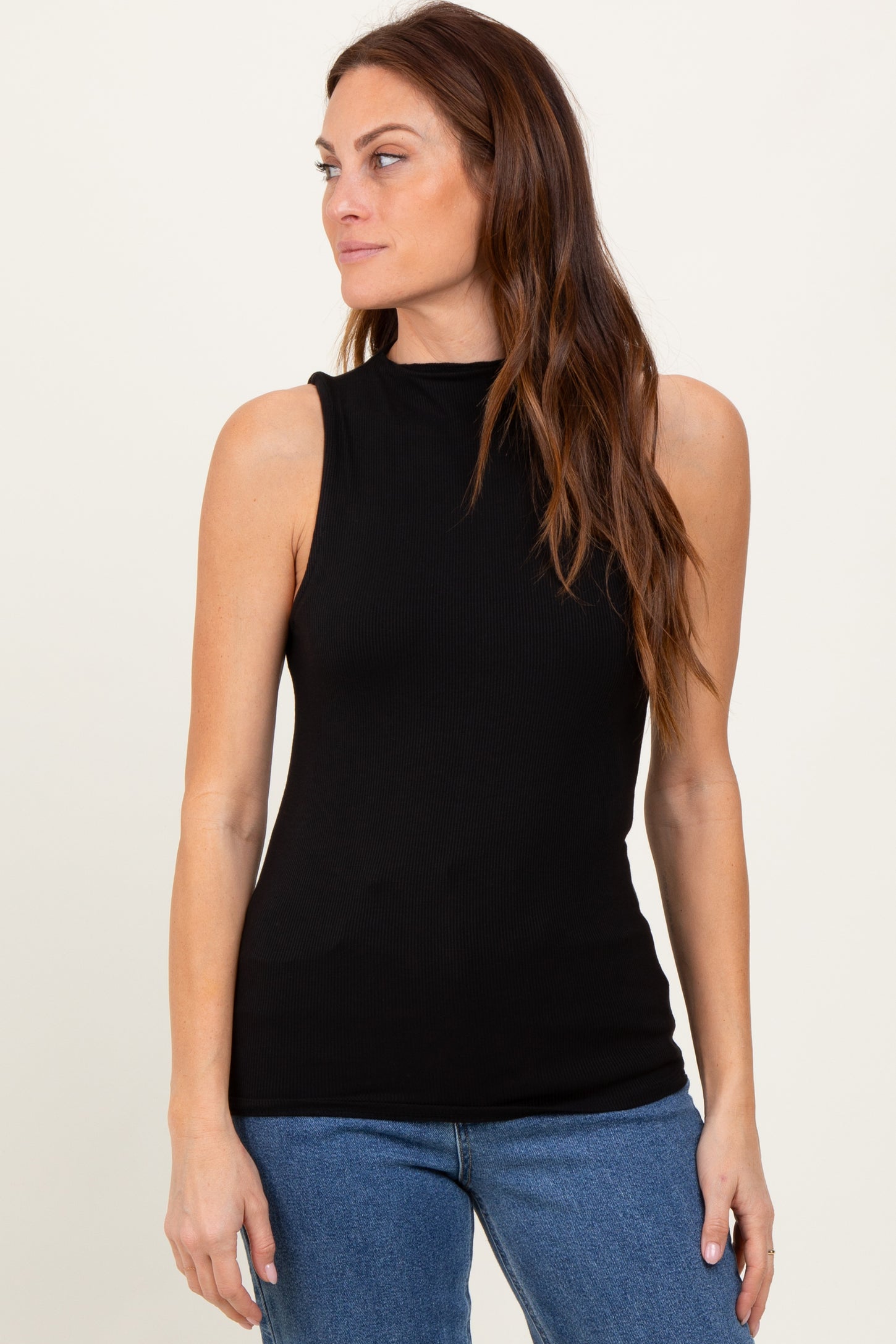 woman wearing a black sleeveless ribbed top with a mock neck and paired with blue jeans