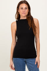 woman wearing a fitted black sleeveless top with a high neckline and styled hair, paired with blue jeans