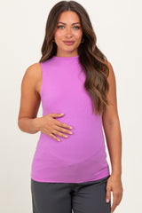 woman wearing a light purple sleeveless maternity top and gently holding her baby bump