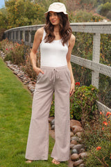 woman wearing a white ribbed maternity tank top and beige striped wide-leg pants with a drawstring waist