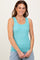 woman wearing a teal ribbed tank top, smiling, styled with layered necklaces and light blue denim shorts