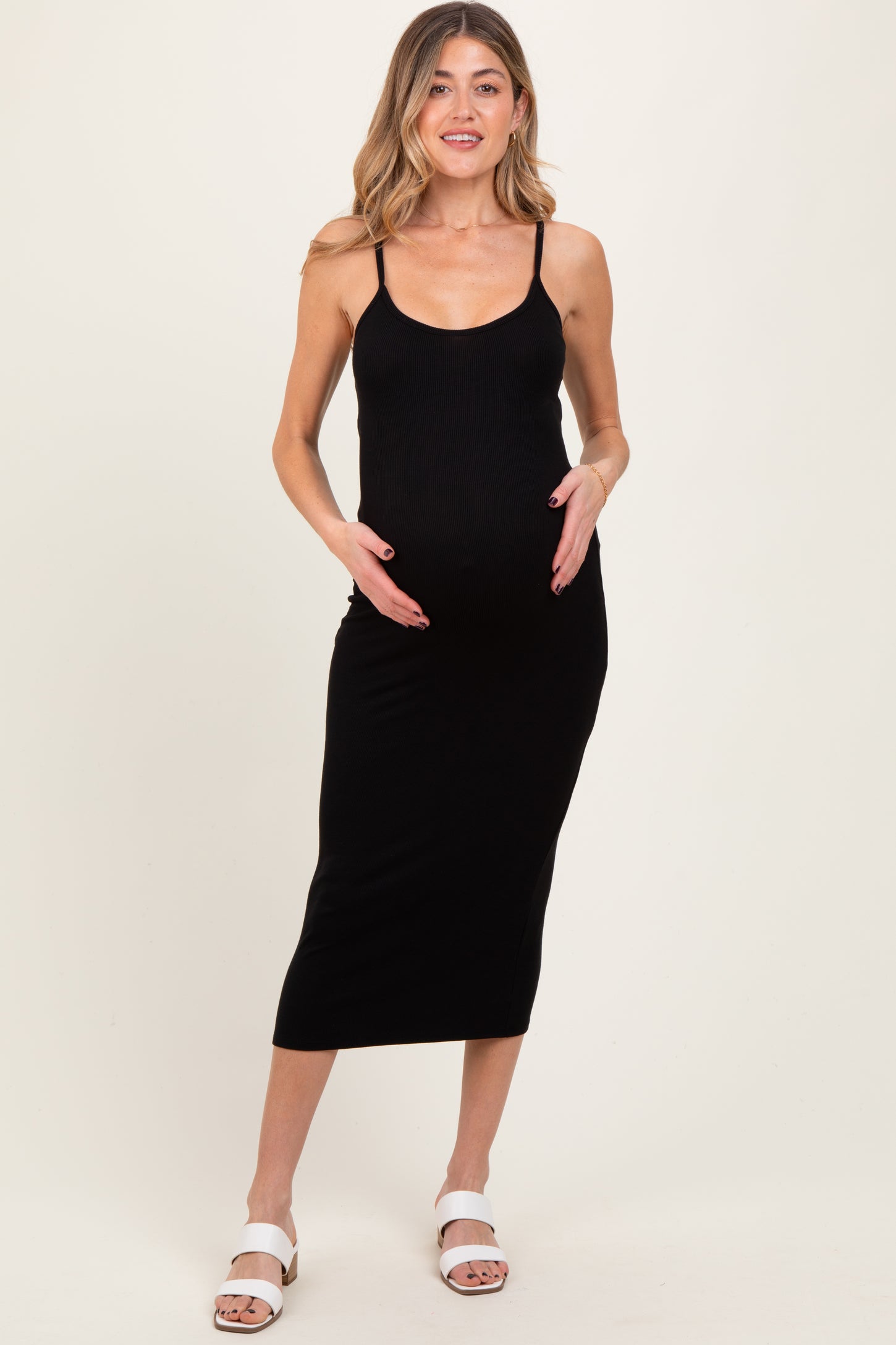 woman wearing a black ribbed maternity dress with thin straps and a baby bump visible