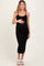 woman wearing a black ribbed maternity dress, showing her baby bump, standing in a relaxed pose
