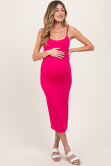 woman wearing a vibrant pink maternity midi dress, showing her baby bump with a hand on her stomach