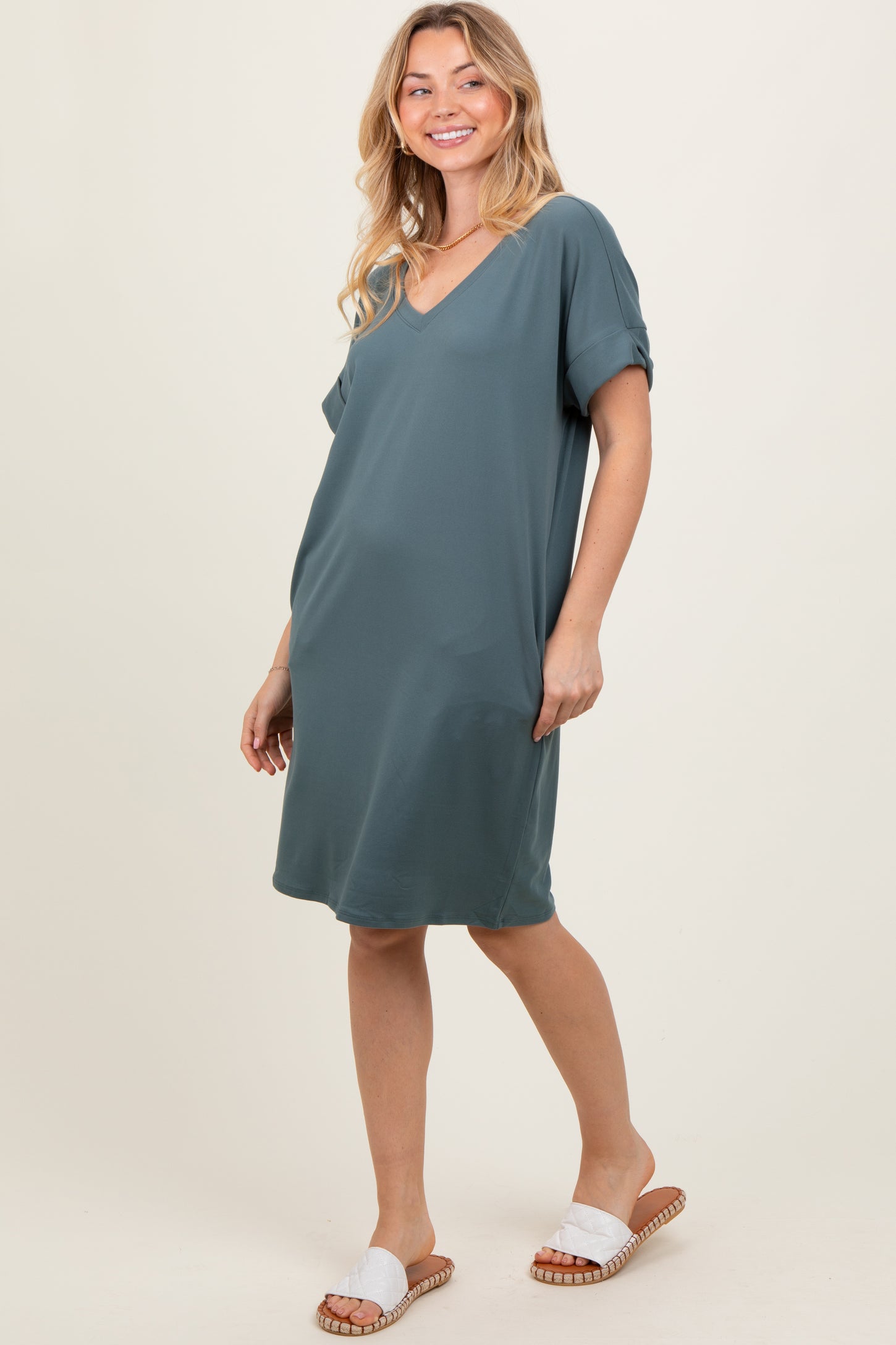 woman wearing a teal short sleeve v-neck dress and white slide sandals