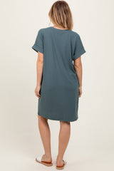 woman wearing a loose-fitting teal short sleeve dress, shown from the back
