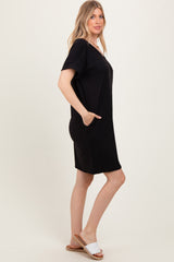 woman wearing a black short sleeve loose fit dress with pockets and casual slide sandals