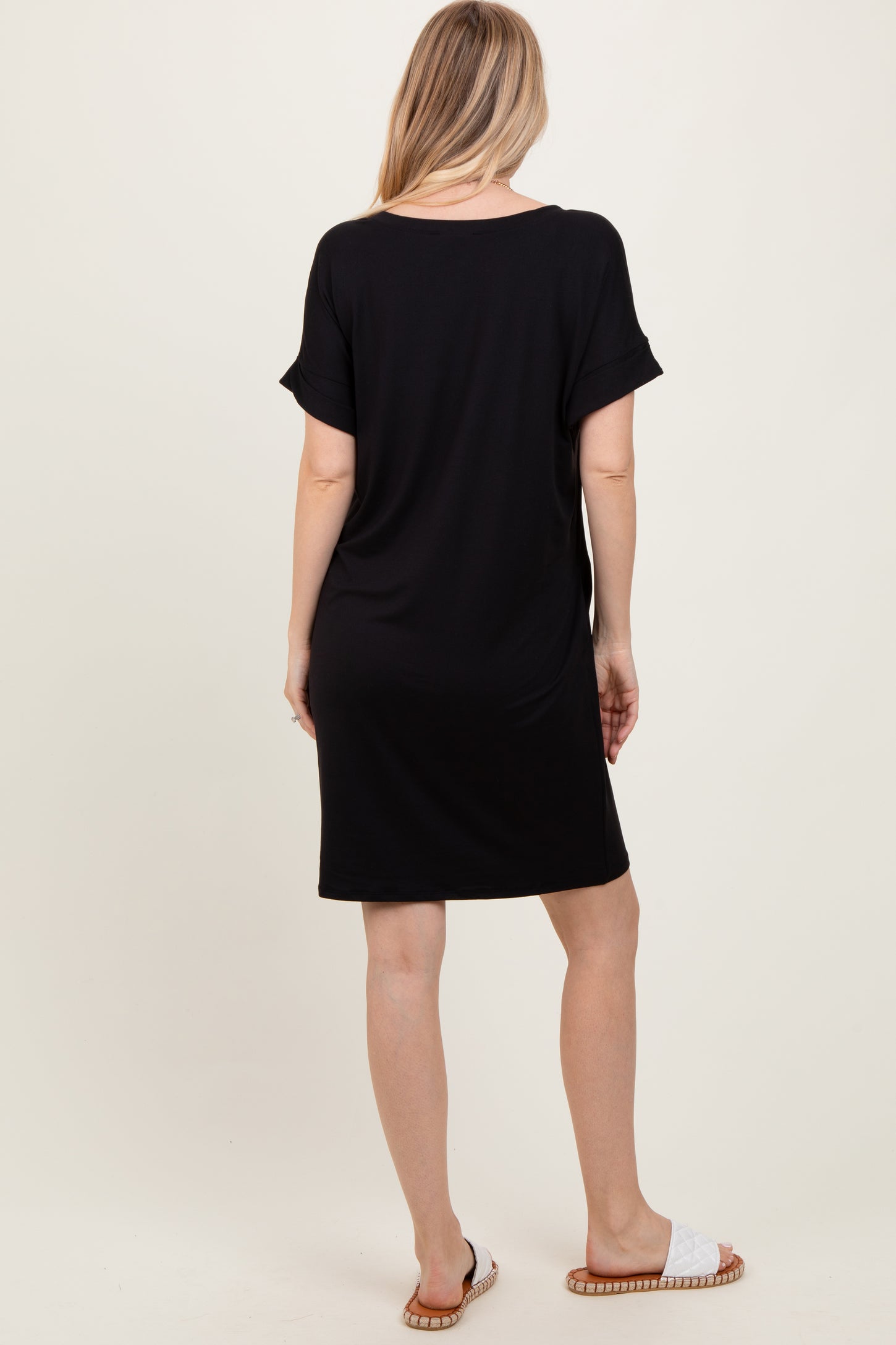 woman wearing a black short sleeve dress, viewed from the back, with a loose fit and slouchy neckline.
