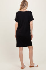 woman wearing a black short sleeve dress, viewed from the back, with a loose fit and slouchy neckline.
