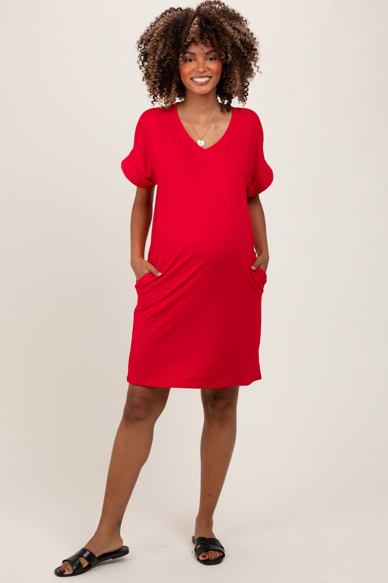 woman wearing a red short sleeve maternity dress with pockets and a visible baby bump