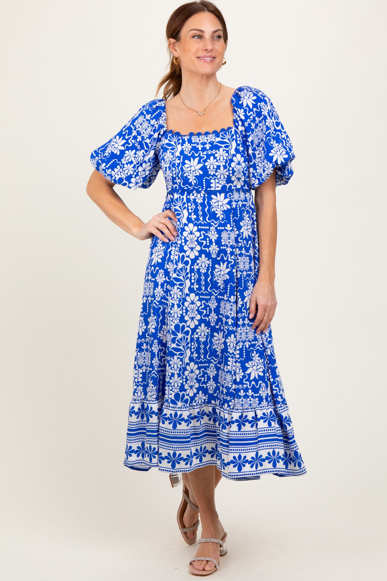 woman wearing a blue floral print puff sleeve midi dress with a square neckline and a flared skirt