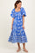 woman wearing a blue floral print midi dress with puff sleeves and a square neckline, standing on a light background