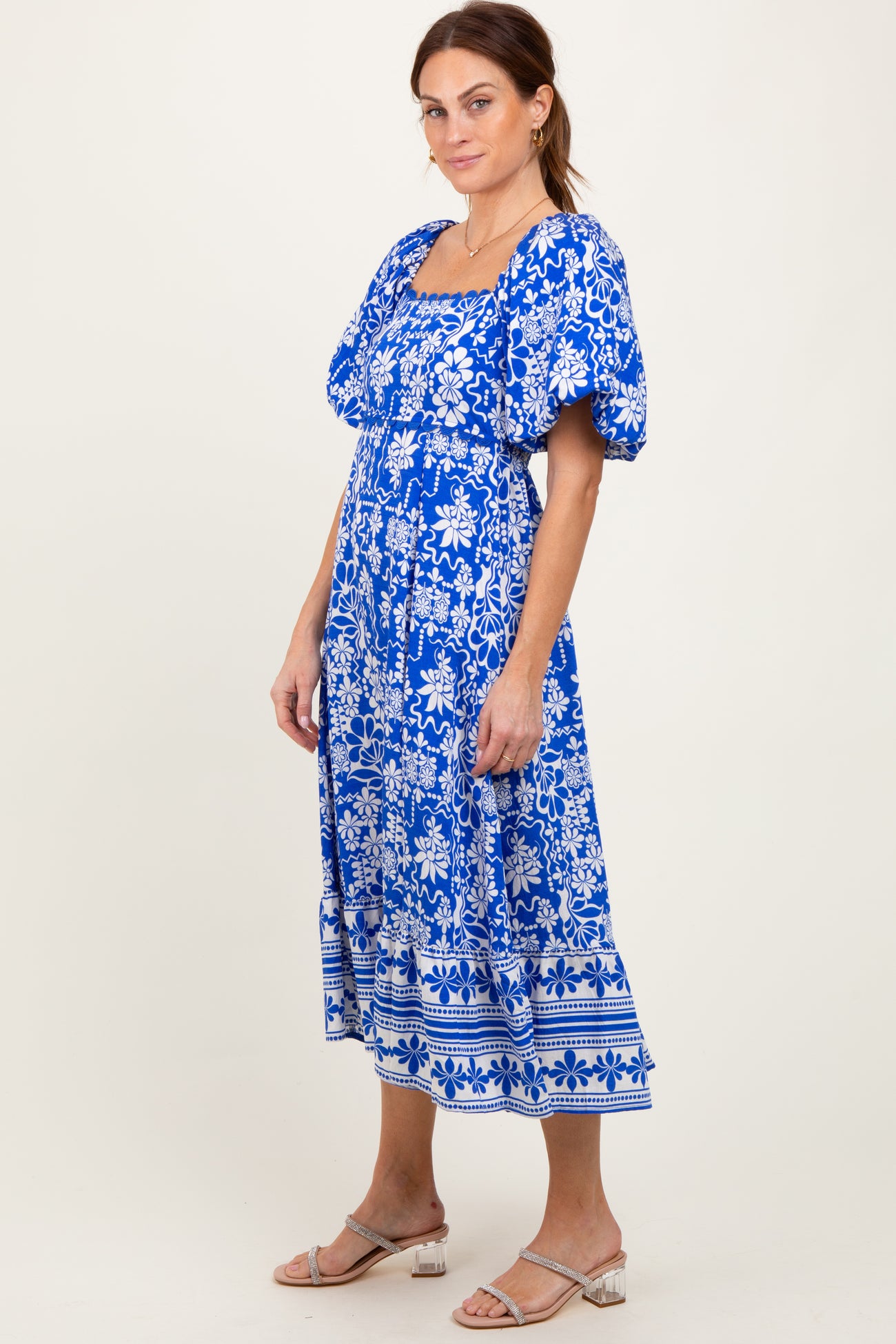 woman wearing a blue floral print midi dress with puff sleeves and a square neckline