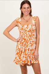 woman wearing an orange and white floral patterned sundress with ruffled straps and a smocked bodice