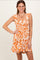 woman wearing an orange and white floral patterned sundress with ruffled straps and a smocked bodice