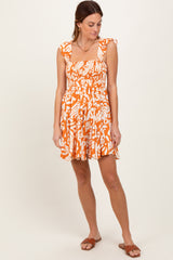 woman wearing an orange and white patterned sundress with ruffled straps and a smocked bodice