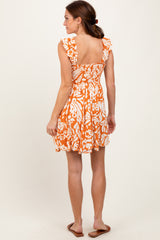 woman wearing an orange and white patterned sundress with ruffled sleeves and a smocked back