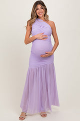woman wearing a purple one-shoulder maternity gown with a flowing skirt and holding her baby bump