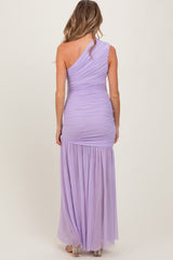 woman wearing a lilac one-shoulder maternity gown with ruched detailing and a flowing skirt