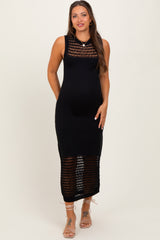 woman wearing a black knitted maternity dress with a sheer bottom and standing with a visible baby bump