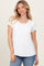 woman wearing a white short sleeve top with a pocket, standing against a light background