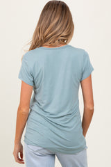 woman wearing a light blue maternity top with short sleeves, showing a gentle drape at the back