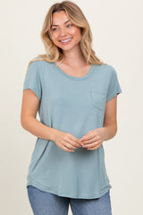 woman wearing a light blue short sleeve top with a pocket and relaxed fit, smiling at the camera