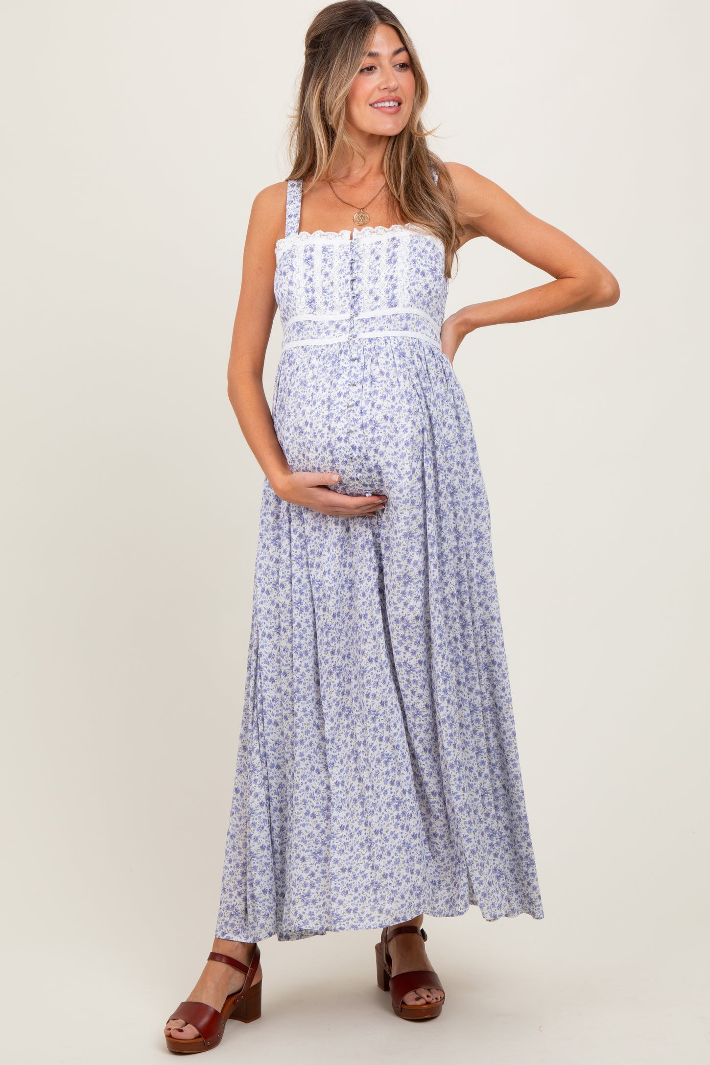 woman wearing a light blue floral maternity maxi dress and holding her baby bump