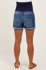 woman wearing dark wash denim maternity shorts with a frayed hem, showing the back view and no visible baby bump