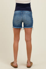 woman wearing maternity denim shorts in a light blue wash with frayed hem and distressed details