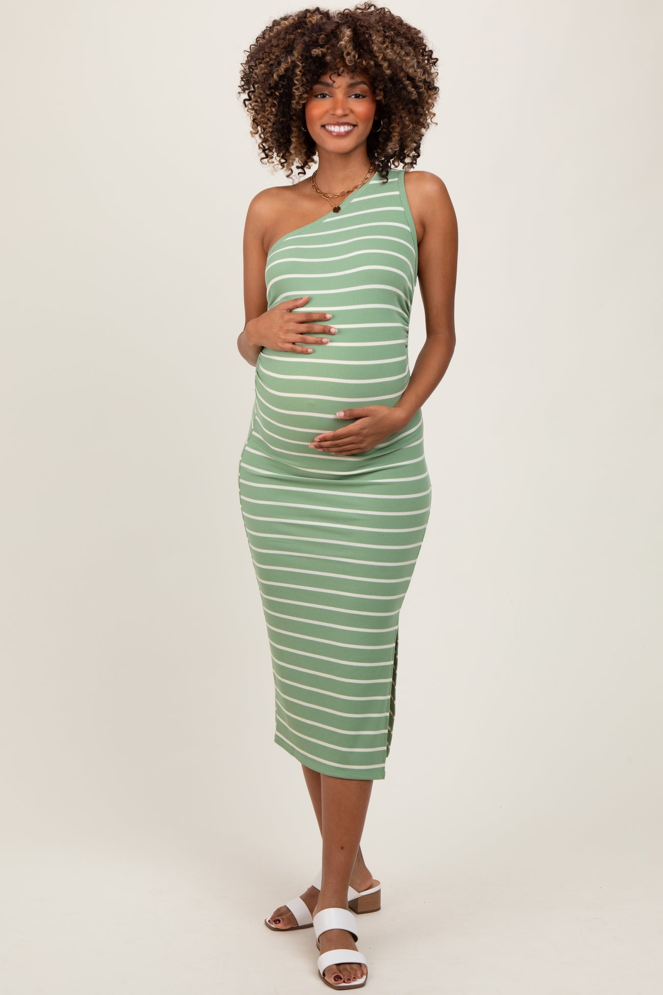 woman wearing a green and white striped one-shoulder maternity dress showcasing her baby bump