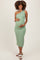 woman wearing a green and white striped one-shoulder maternity dress showcasing her baby bump